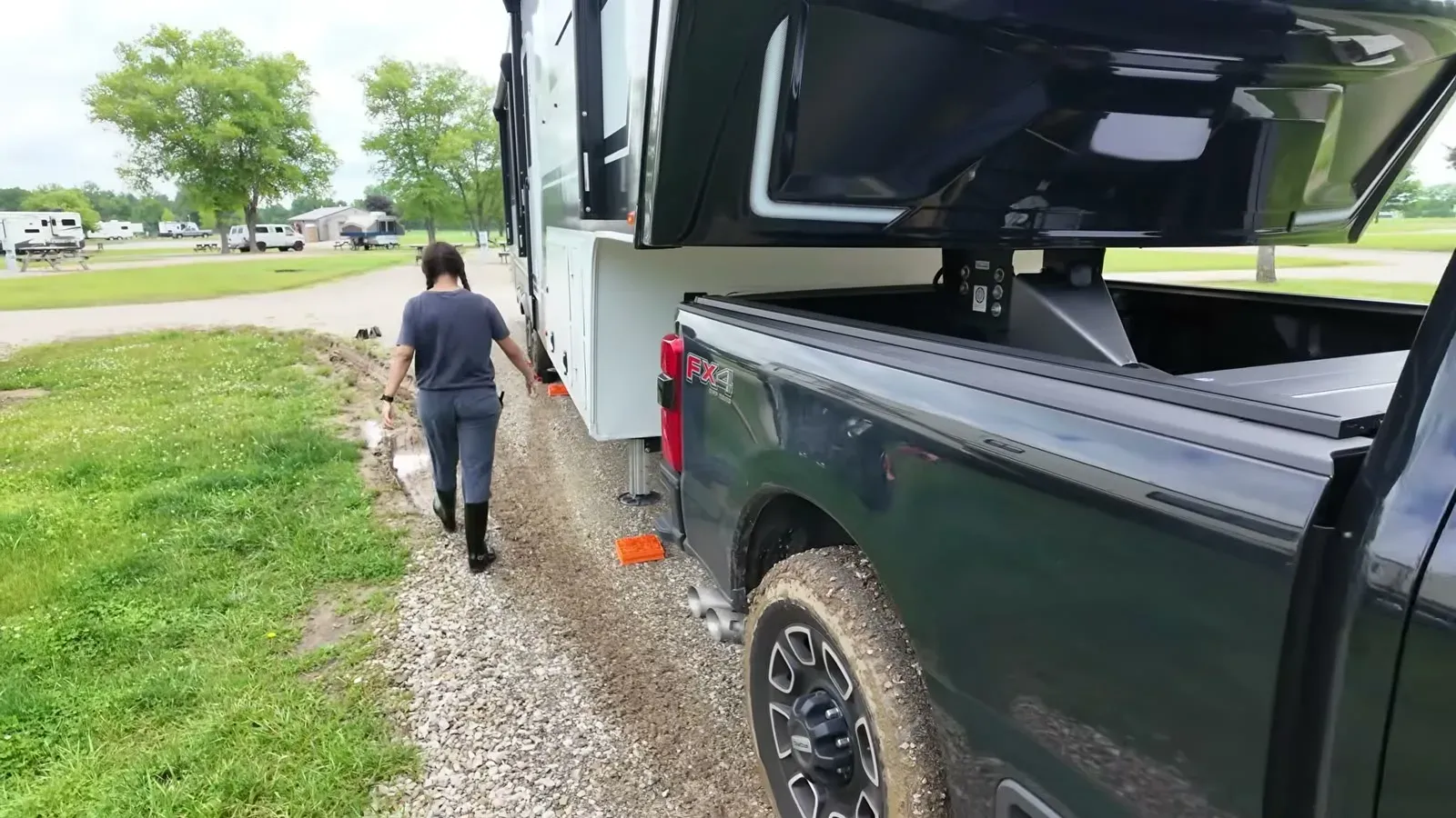 Fabiola walking the soggy strip of grass and gravel beside the rig at our Johnson County Park site, fresh mud everywhere.