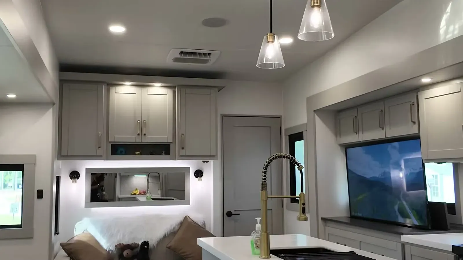 The 3515's kitchen island with its gold faucet, pendant lights, and the TV and cabinets that make the living area feel like a small apartment.