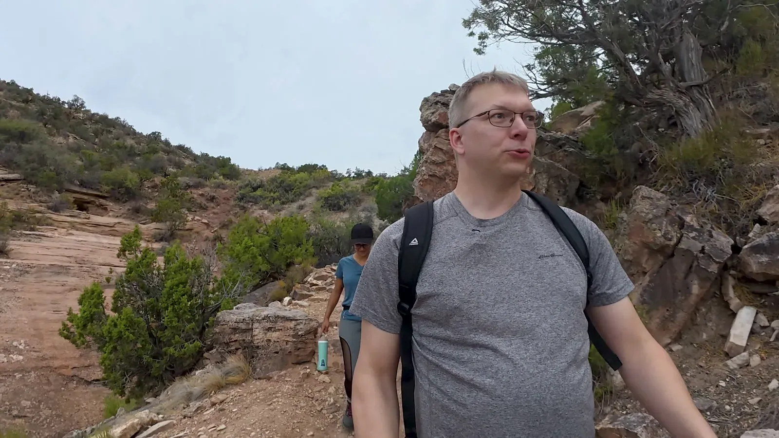 Nathan on the Coke Ovens Trail with Fabiola behind him among the juniper and red rock