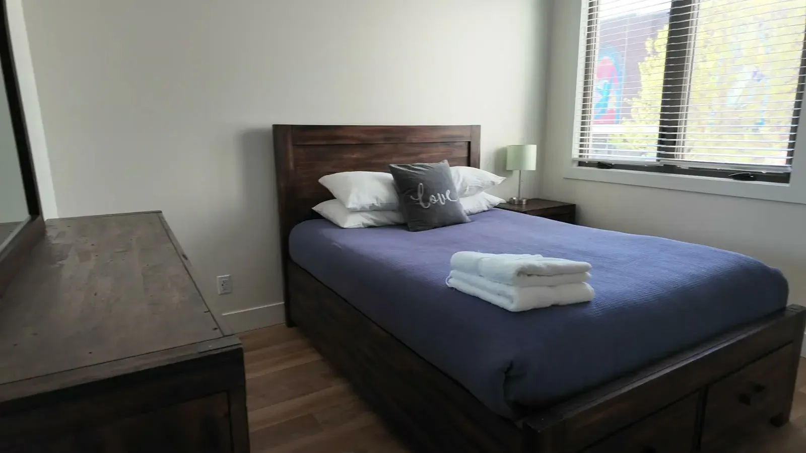 The bedroom at our Traverse City Airbnb, fresh towels folded on the bed and afternoon light coming through the blinds.