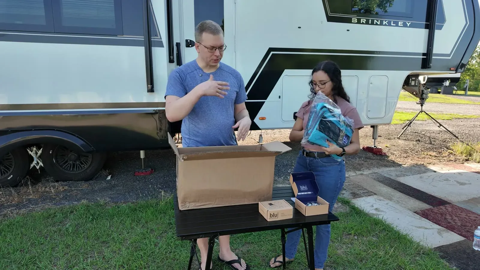 Nathan and Fabiola unboxing the Blu Tech AR3 Essential Bundle on a folding table next to the Brinkley.