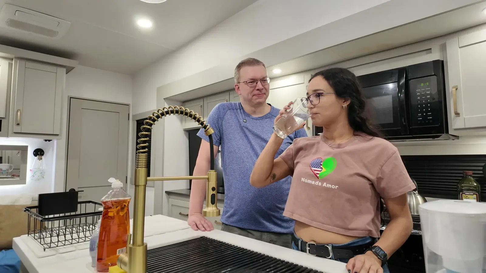 Fabiola taking the first sip of filtered water at the kitchen sink for the taste test.