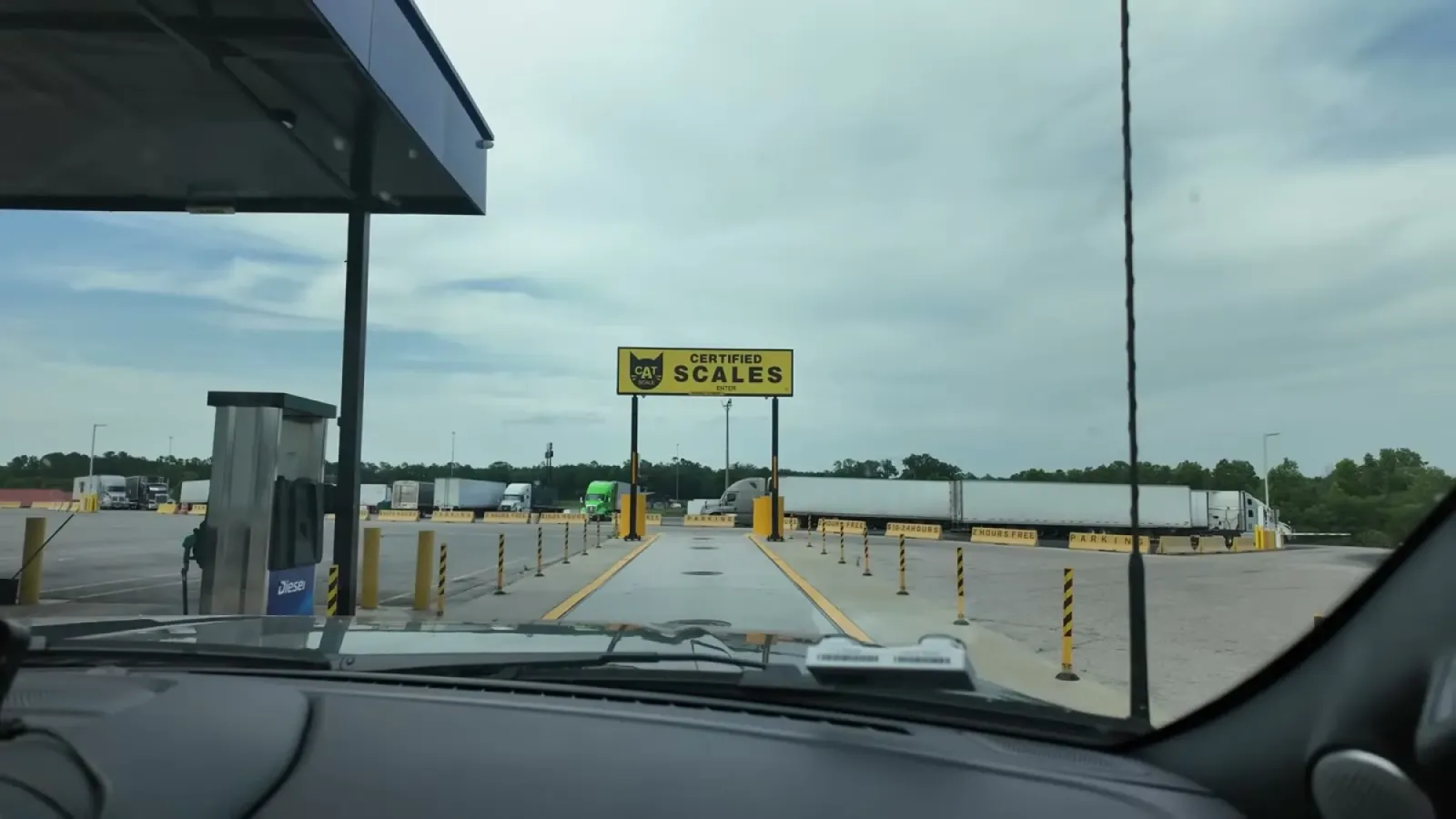 View through the truck windshield approaching the yellow CAT certified scales sign and scale lane at a travel center