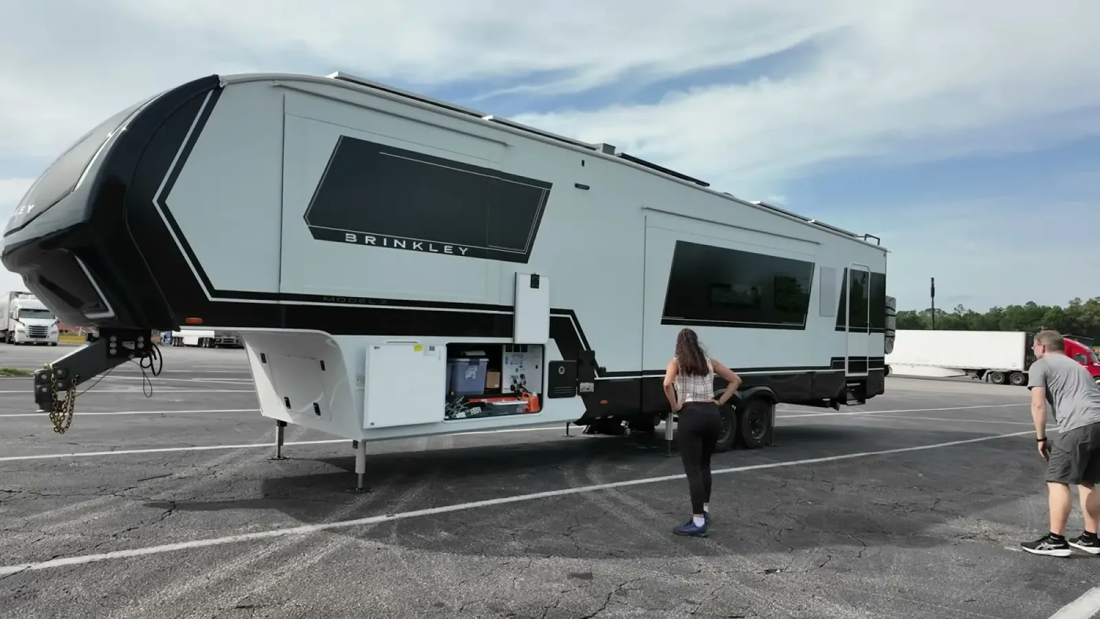 Unhitched Brinkley fifth wheel sitting nose high on its landing gear in a sloped parking lot