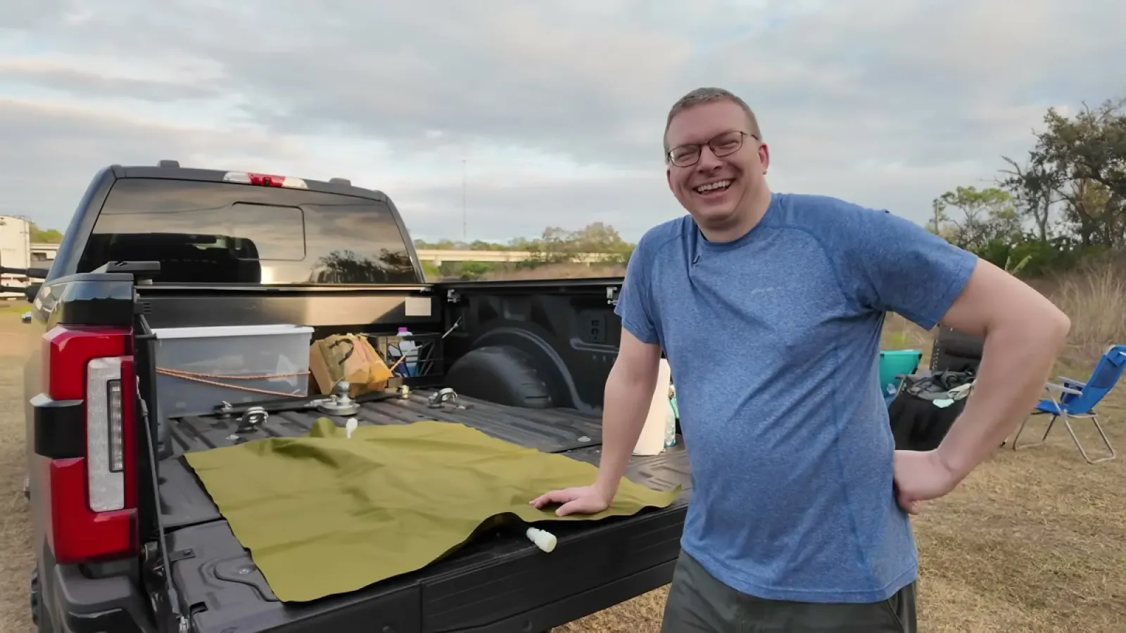Nathan standing at the tailgate with the empty olive-green RV water bladder spread flat across the truck bed