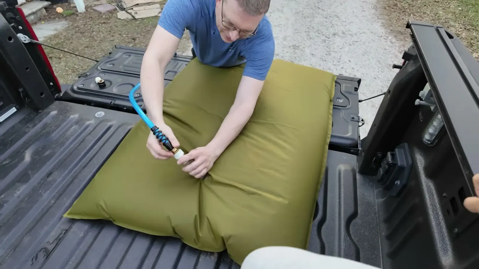 Nathan attaching a blue hose fitting to the water bladder as it fills and puffs up in the truck bed