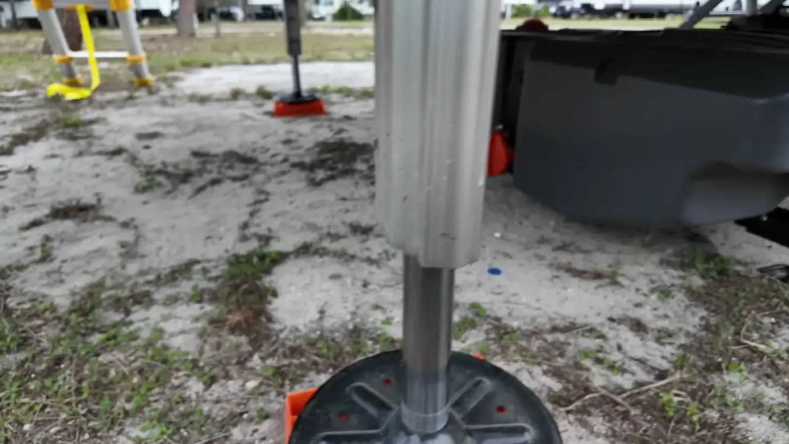 Metal leveling jack foot of a fifth wheel resting on sandy ground, one of the paths ants use to climb into an RV
