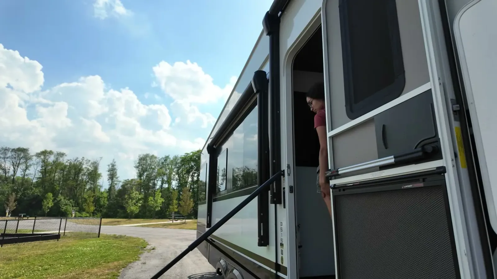 Fifth wheel slide-out extended above the open entry door, with Fabiola standing inside the doorway