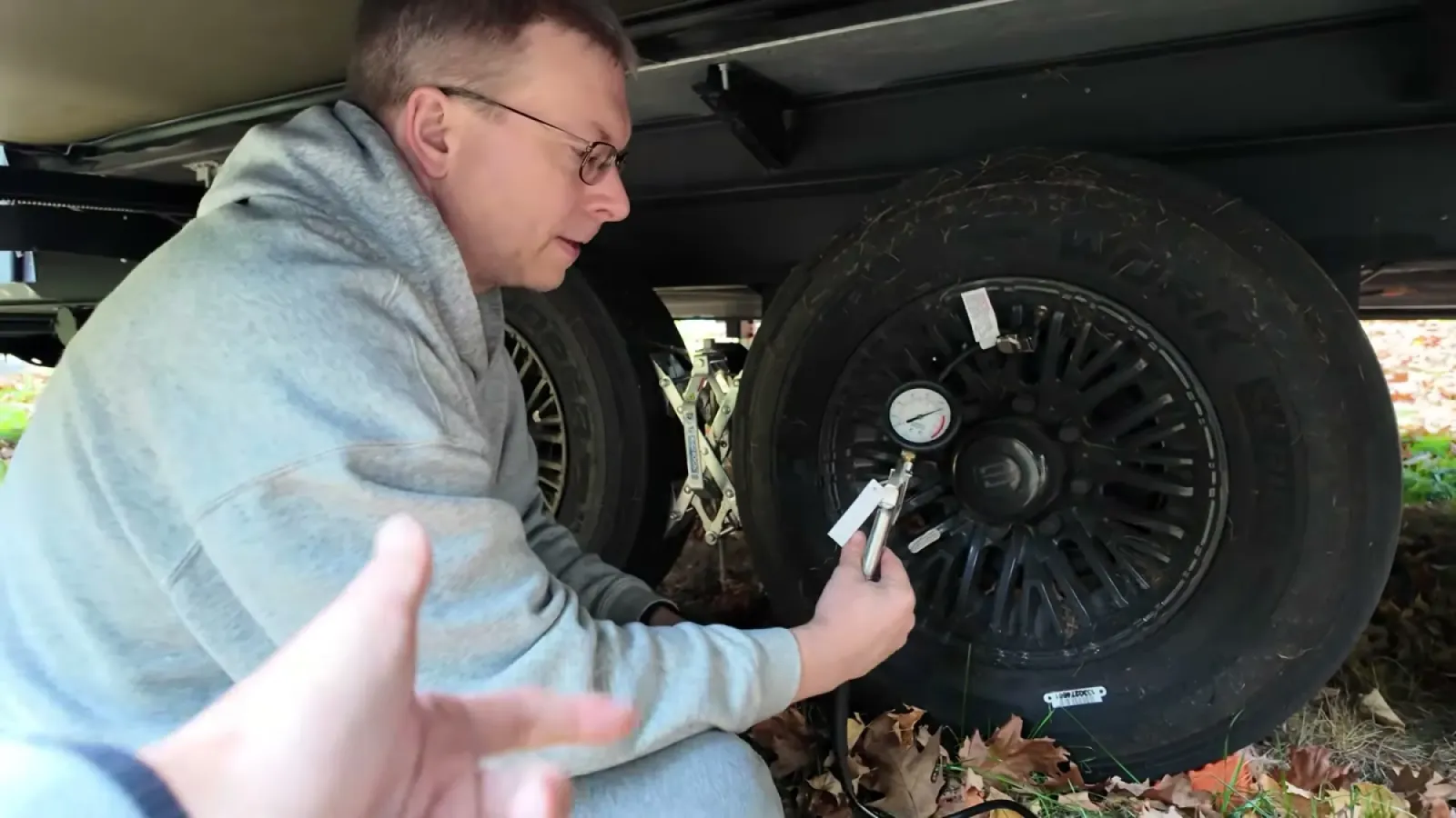 Nathan holding an inflator gauge attached to a fifth wheel trailer tire while airing it up