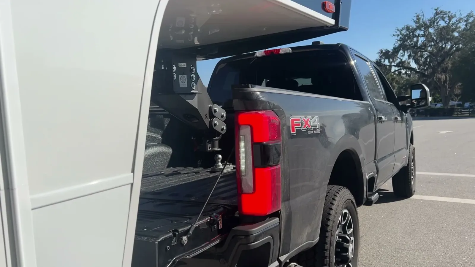 Truck bed with tailgate down and the gooseneck ball visible below the fifth wheel pin box hanging above, lined up just before coupling