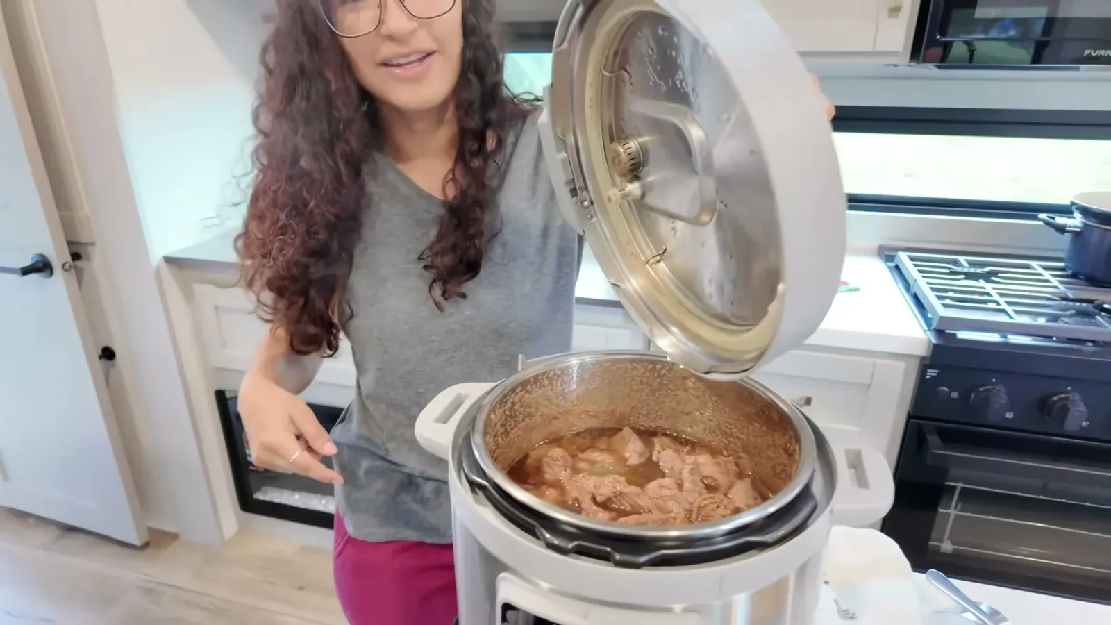 Fabiola abrindo a Instant Pot com um ensopado de carne pronto