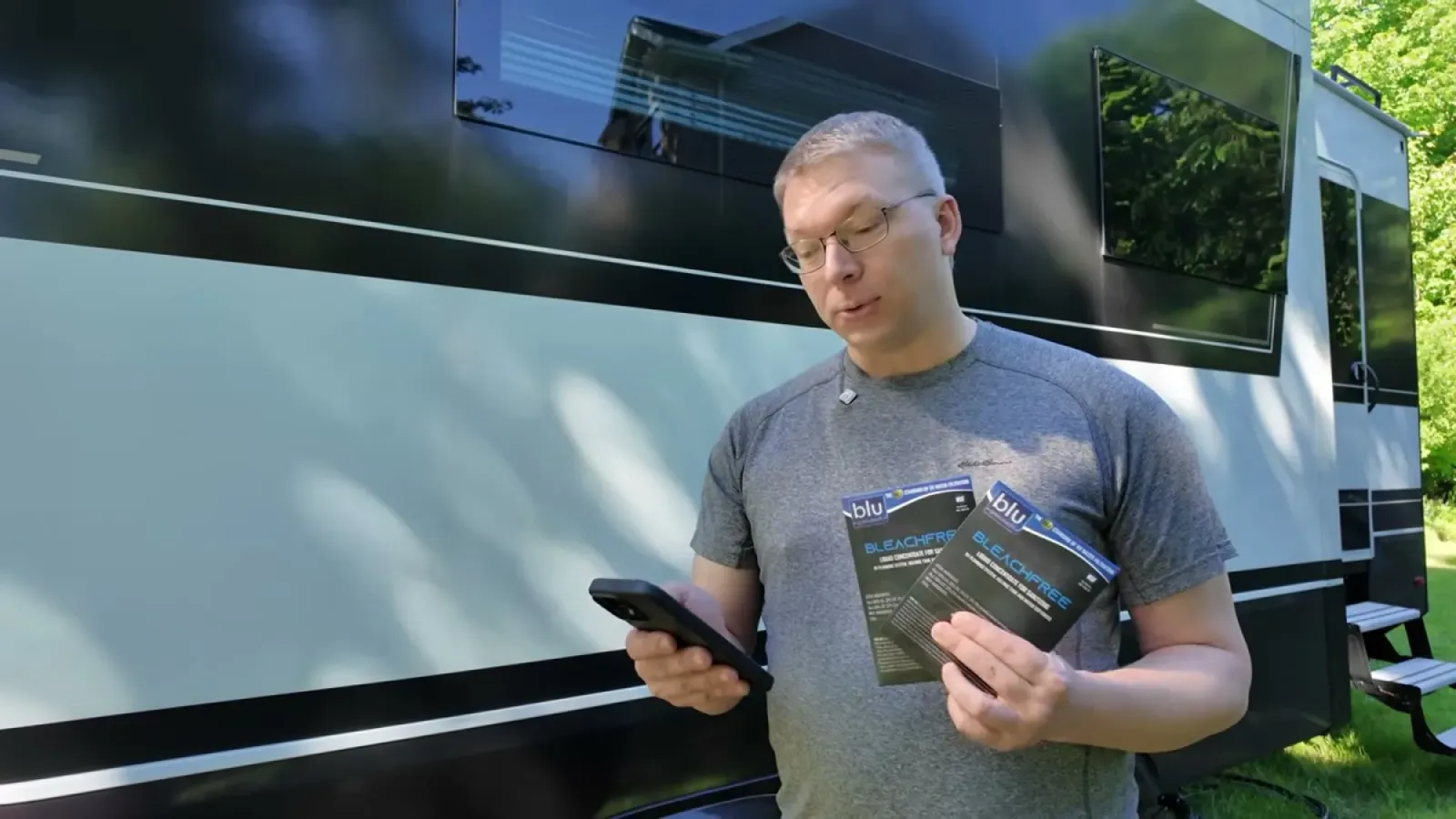 Nathan holding the box of bleach-free RV tank sanitizer packets beside the fifth wheel