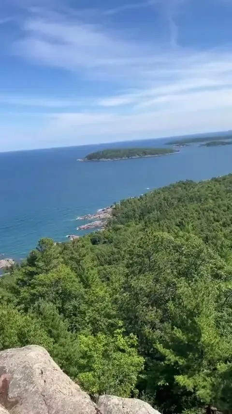 The Lake Superior shoreline curving toward the forested point near Presque Isle, seen from the second overlook on Sugar Loaf Mountain.