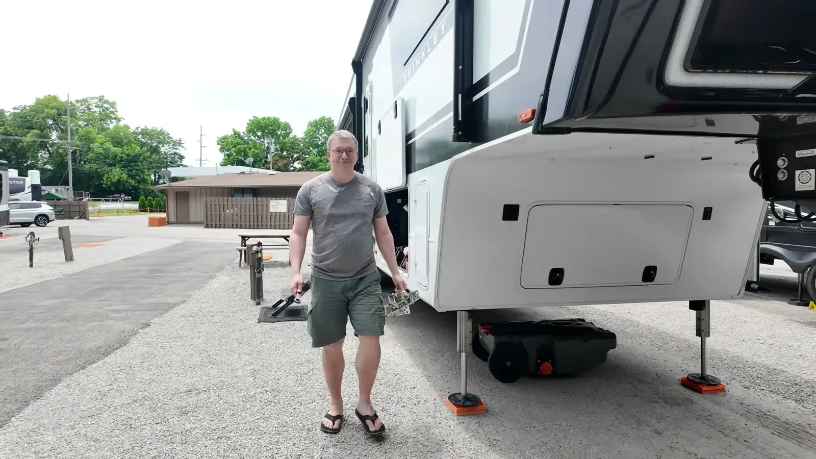 Nathan walking gear along the fifth wheel after squeezing it into the gravel site, leveling pads already down.