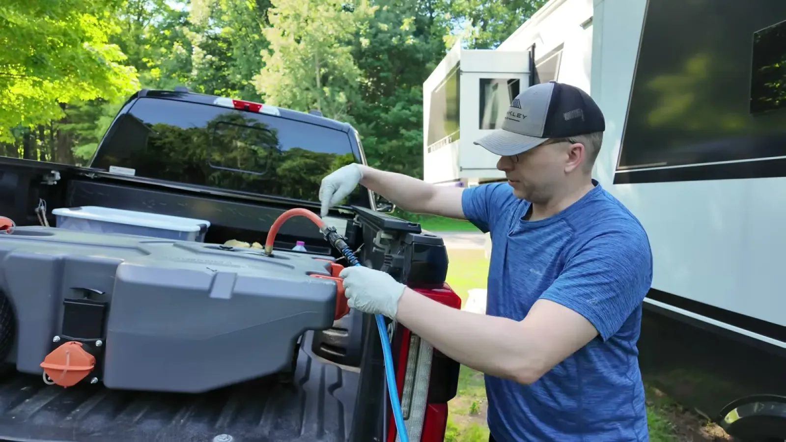 Nathan in gloves connecting the macerator pump and hose to the portable waste tank in the bed of the truck