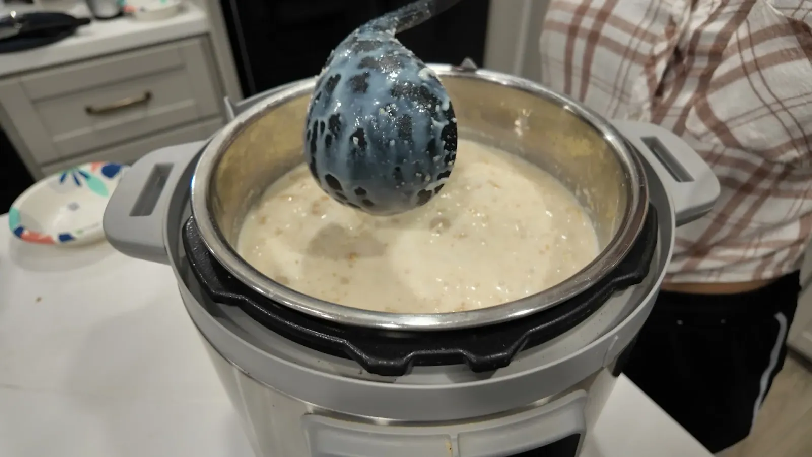 Canjica cremosa vista de cima dentro da Instant Pot, com uma espátula apoiada na panela