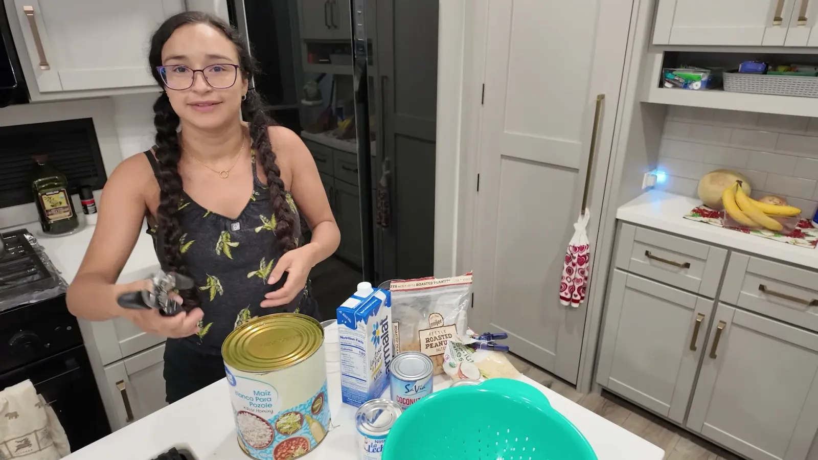 Fabiola na cozinha do motorhome com uma lata grande de milho branco, leite condensado, leite de coco, leite longa vida e amendoim sobre a bancada