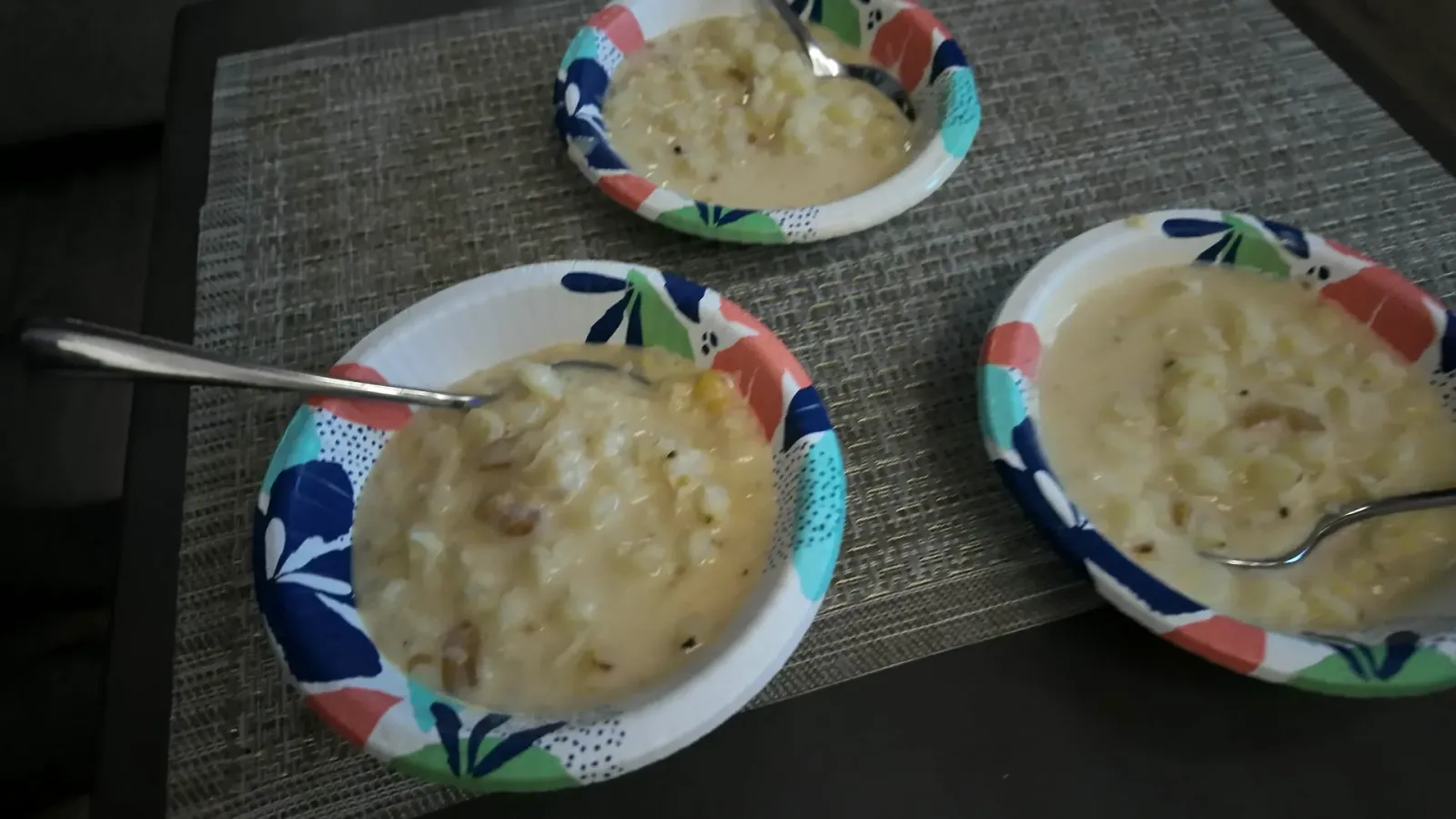Three bowls of finished canjica with spoons on a placemat in the RV living room