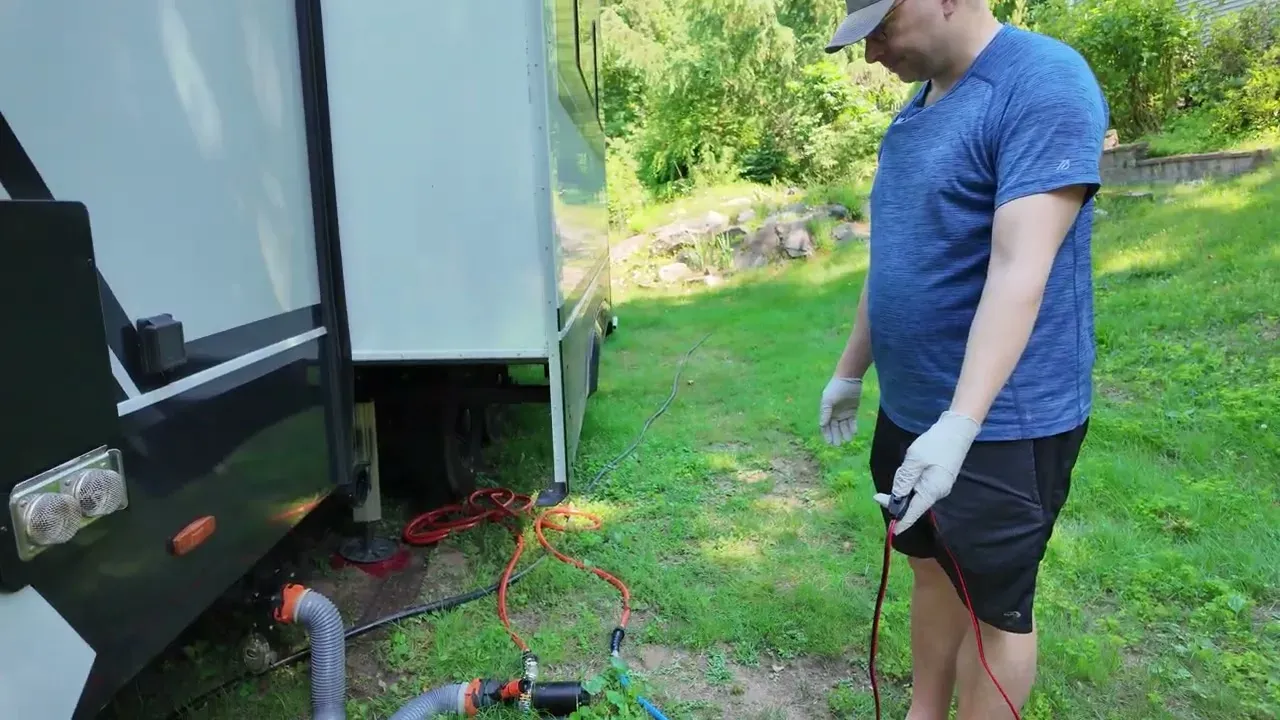Nathan in gloves standing beside the macerator pump and hoses connected to the fifth wheel waste outlet