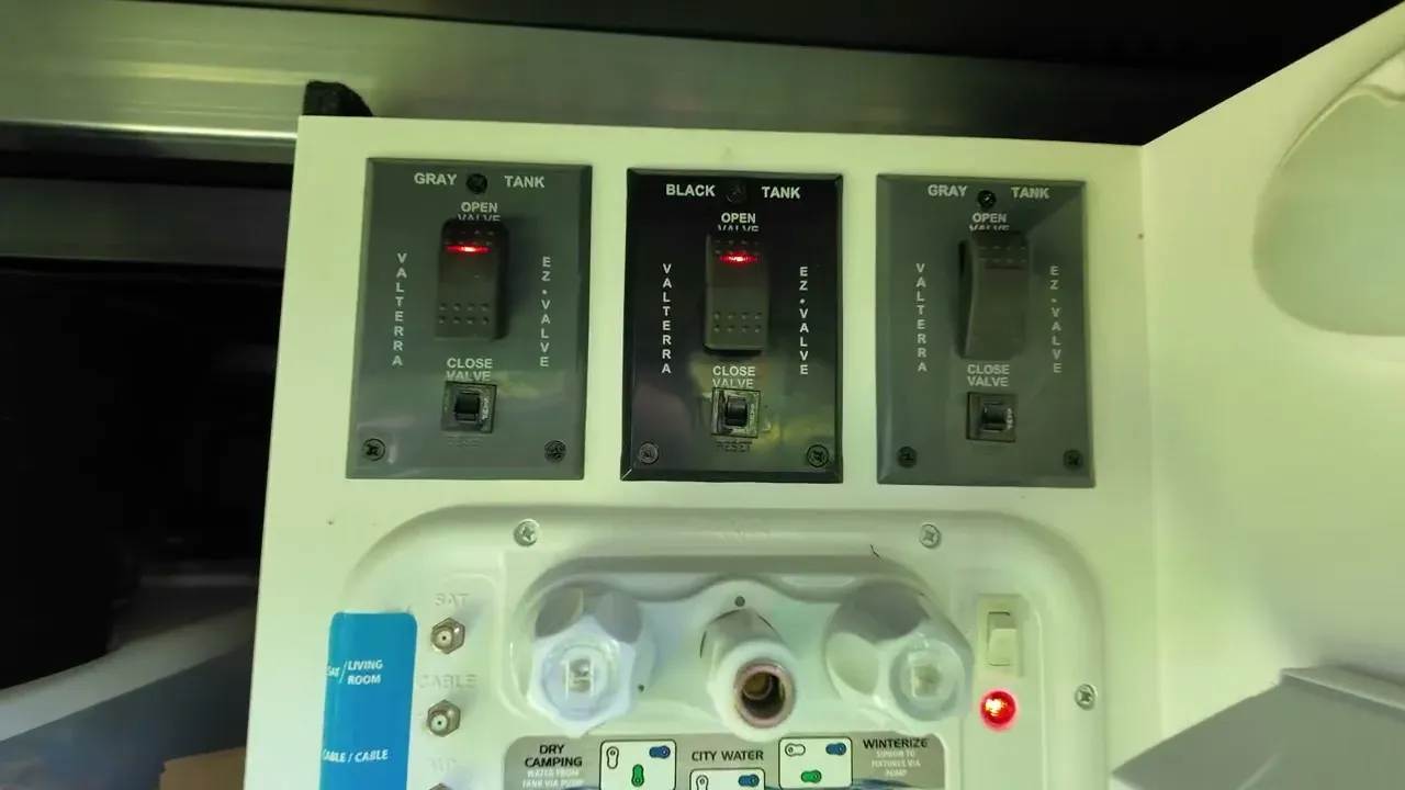 The gray and black tank valve panel inside the RV utility bay with the valve switches labeled