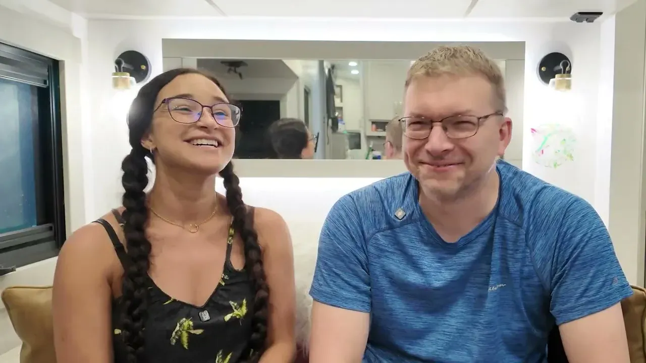 Nathan and Fabiola sitting together on the RV couch talking to the camera