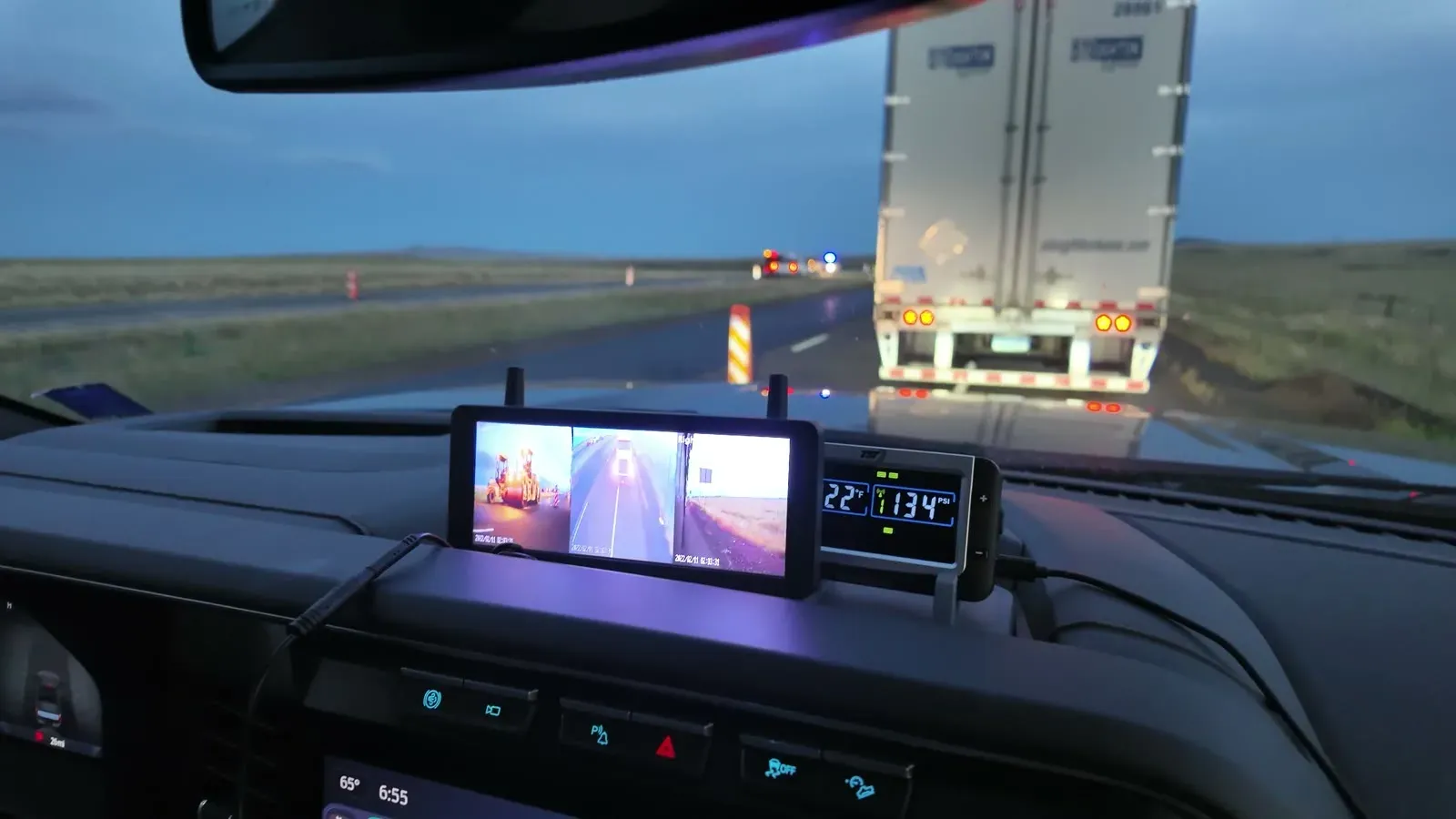 The RV camera monitor on the truck dash showing three camera views while stopped behind a semi in road construction