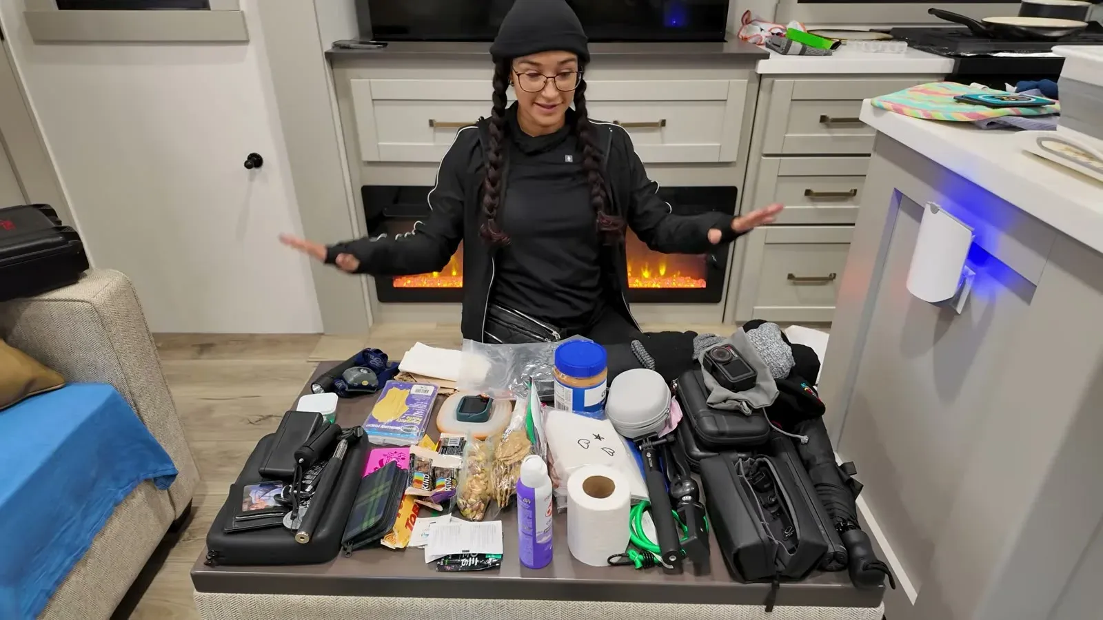 Fabiola standing over a table buried in snacks, layers, and gear inside the RV while packing for a single day hike.