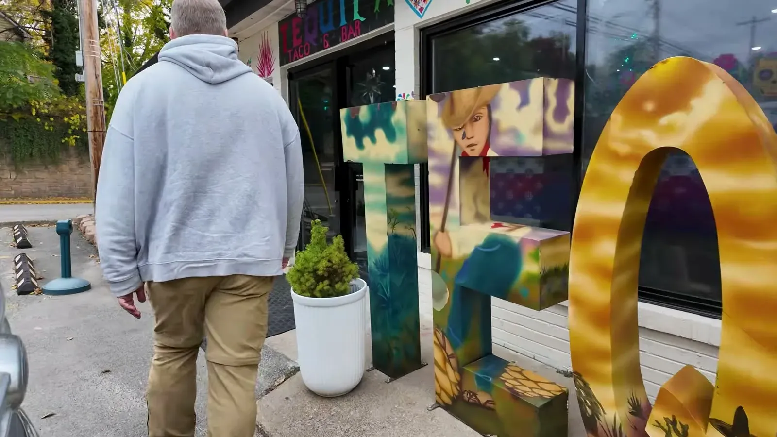Nathan walking past the painted taco mural letters on the way into the tequila bar after the hike.