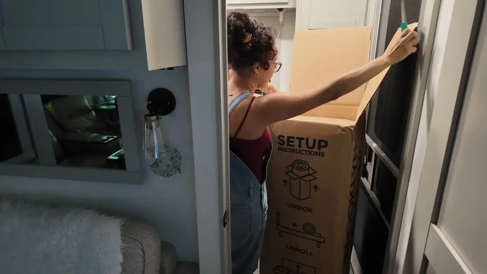 Carrying the boxed RV mattress through the door of the fifth wheel. It ships compressed, which is how it fits through an RV doorway and down the hallway.