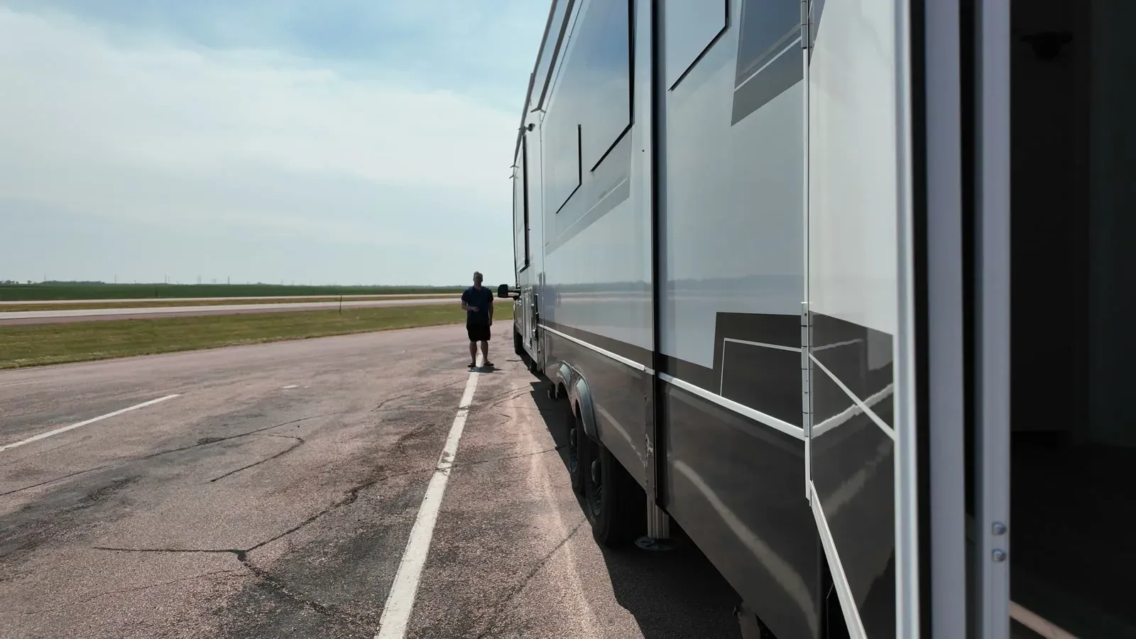 Nathan standing beside the Brinkley fifth wheel at a South Dakota rest area with semi trucks parked nearby