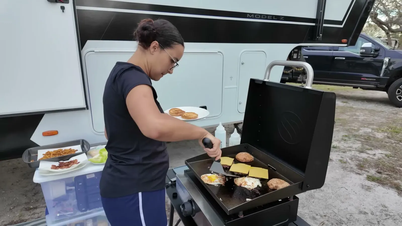 Cheese melting onto a burger patty on the griddle while a toasted bun waits alongside