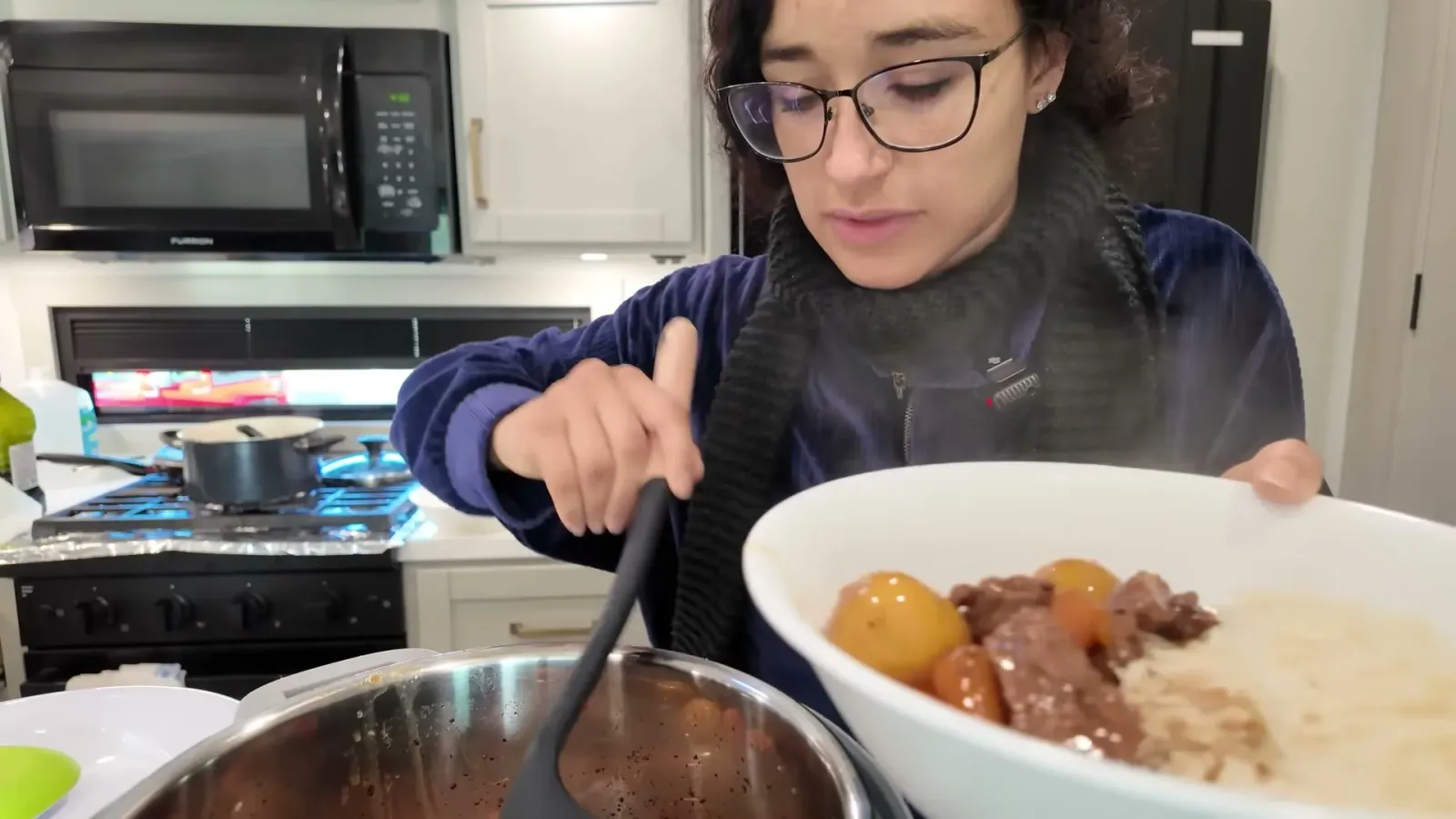 A bowl of beef stew with potatoes and carrots served over white rice in the RV kitchen at the end of a travel day