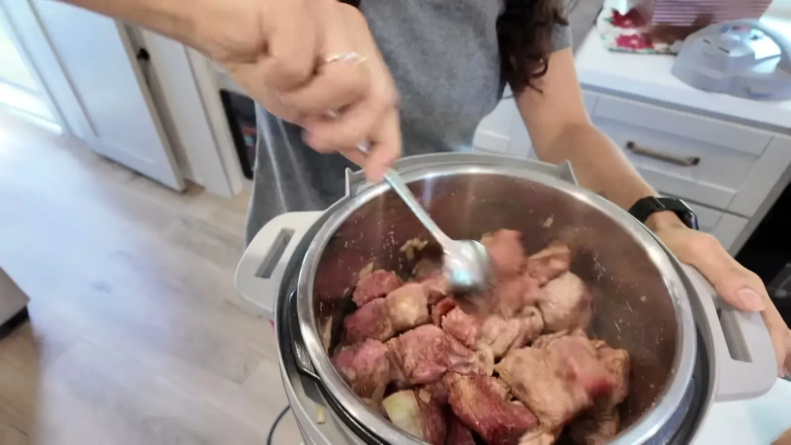 Stew meat browning with onions and garlic in the Instant Pot on sauté, stirred with a spoon before any broth goes in
