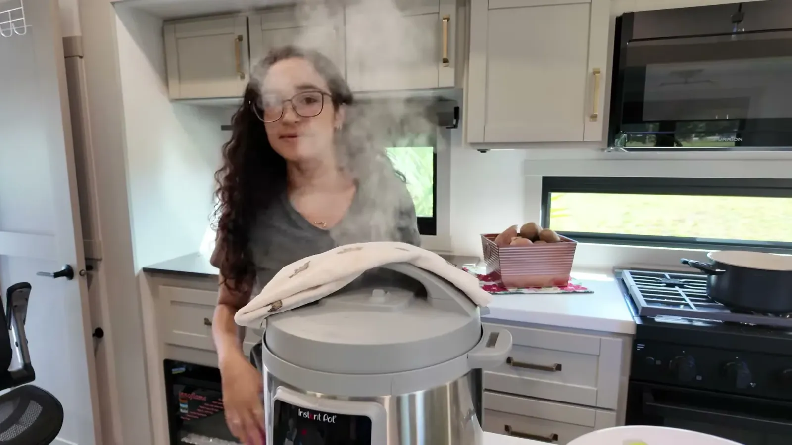 Steam pouring out of the Instant Pot release valve with a kitchen towel laid over it inside the RV