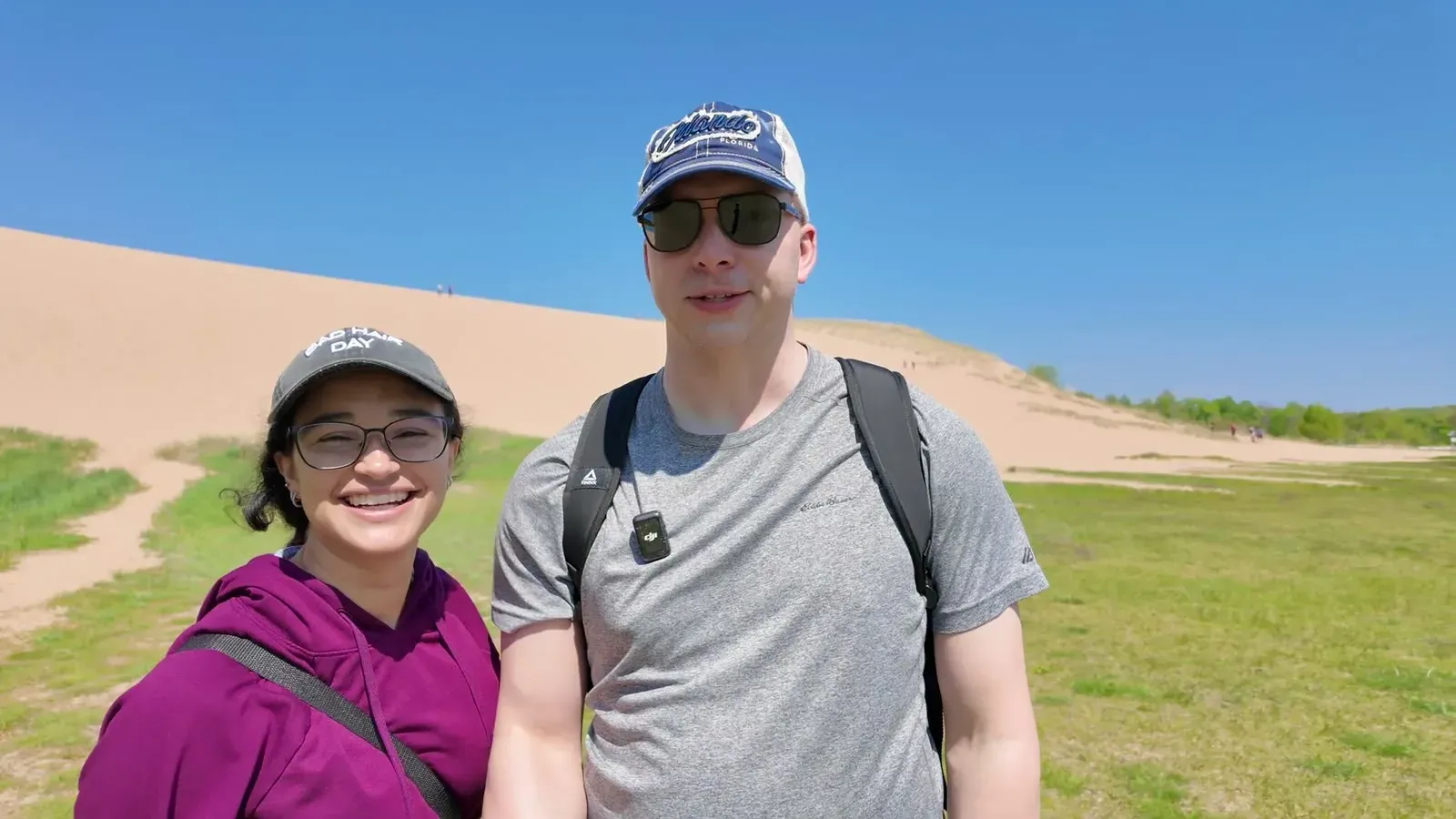 Us at the bottom of the Dune Climb, with the wall of sand rising behind the grass where the trail begins.